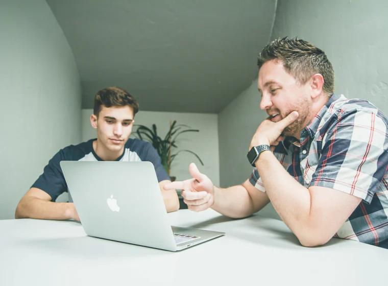 A tutor helping a student on a laptop